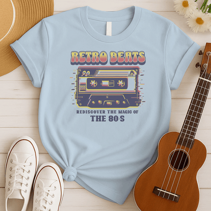 Stylized graphic of a classic audio cassette tape in red, yellow, and blue colors with a glitch effect. Large, distressed orange text above reads "RETRO BEATS". Smaller orange text below reads "REDISCOVER THE MAGIC OF THE 80S". The design evokes vintage music, 80s pop culture, and retro audio technology. Ideal for 80s enthusiasts and music lovers.