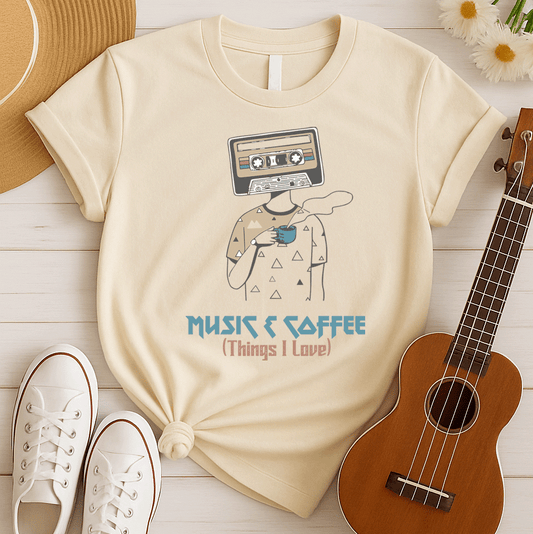 Stylized graphic of a person's body with a vintage brown and black audio cassette tape as its head, holding a blue steaming coffee cup. Small triangle patterns are on the person's beige shirt. Blue distressed text below reads "MUSIC & COFFEE" and red text below that says "(Things I Love)". The design embodies music appreciation, coffee love, and retro nostalgia, ideal for music lovers and coffee enthusiasts.