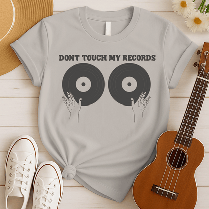 A black background features the bold, capitalized text "DONT TOUCH MY RECORDS" at the top. Below, two large, dark grey vinyl records are depicted side-by-side, with two outlined hands reaching up from the bottom, appearing to cup or touch the records. The design is humorous, symbolizing a possessive love for music, vinyl records, and record collecting, ideal for audiophiles and music fans.
