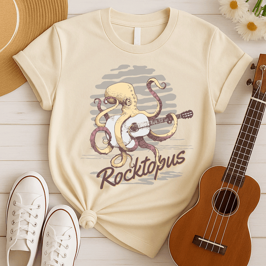 A light grey background with darker grey cloud-like shapes behind a yellowish-beige octopus with reddish-brown tentacles. The octopus is depicted playing a white/light grey acoustic guitar with its tentacles. Below the image, the stylized text "Rocktopus" is visible in brownish-red with a yellow outline. The design is a humorous and unique depiction of music, an octopus, and a guitar, appealing to rock and music fans.