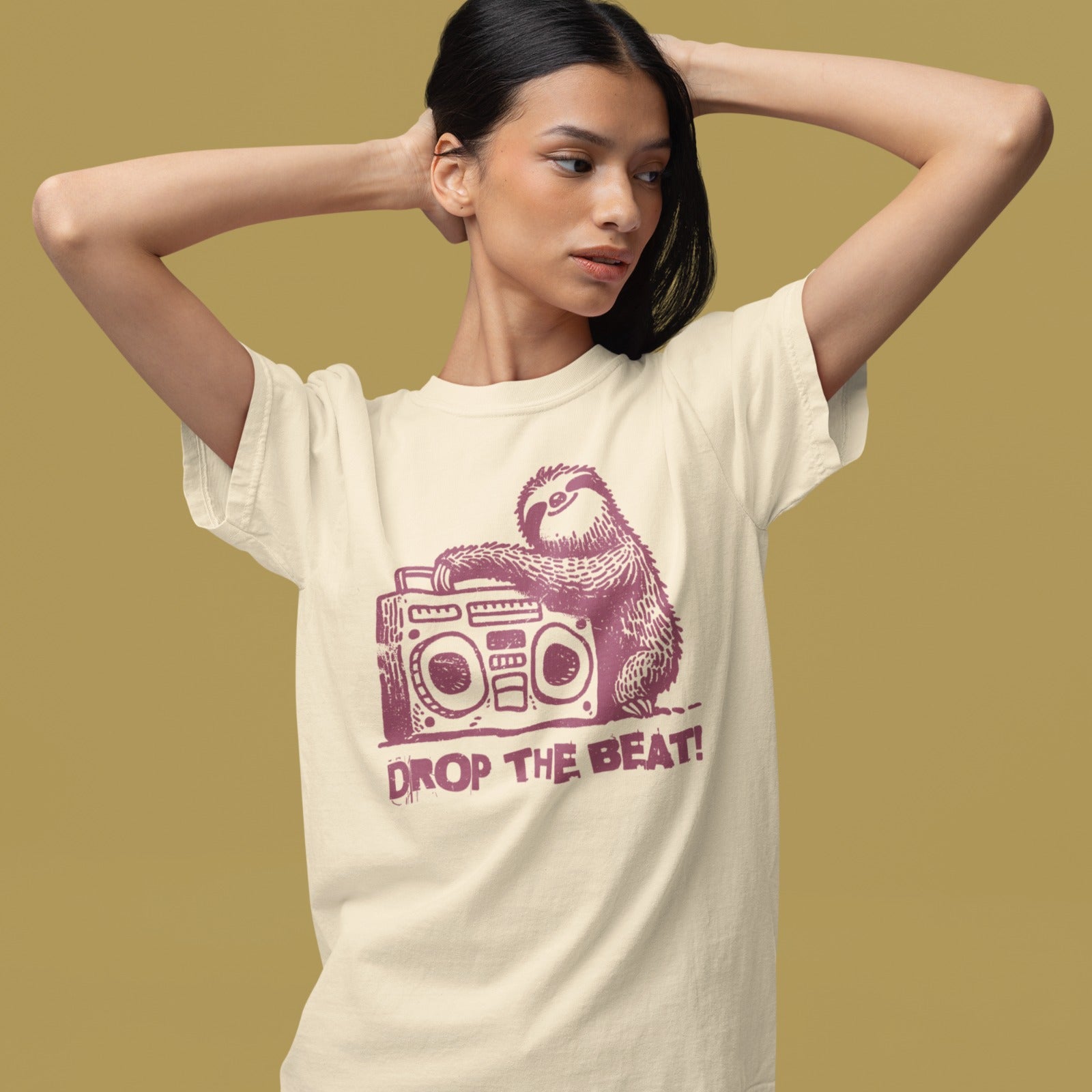 A light grey background features a distressed, red-brown illustration of a fluffy sloth. The sloth is leaning on a large, matching red-brown boombox, which has prominent speakers and controls. Below the sloth and boombox, the distressed text "DROP THE BEAT!" is written in a blocky, red-brown font with a slight splattered effect. The design portrays a relaxed animal enjoying loud music from a retro radio.