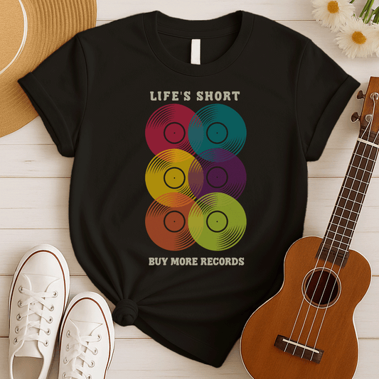 A black background features six vertically stacked, colorful vinyl records (LP records) with visible grooves and black center labels. The record colors include red, teal, yellow, purple, orange, and green. At the top, the distressed text "LIFE'S SHORT" is present, and at the bottom, the distressed text "BUY MORE RECORDS" is visible. The design is a clear celebration of vinyl culture and music collecting.