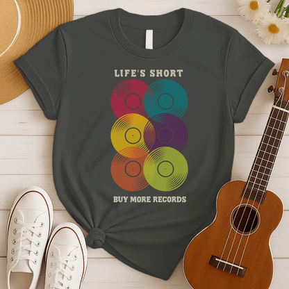 A black background features six vertically stacked, colorful vinyl records (LP records) with visible grooves and black center labels. The record colors include red, teal, yellow, purple, orange, and green. At the top, the distressed text "LIFE'S SHORT" is present, and at the bottom, the distressed text "BUY MORE RECORDS" is visible. The design is a clear celebration of vinyl culture and music collecting.